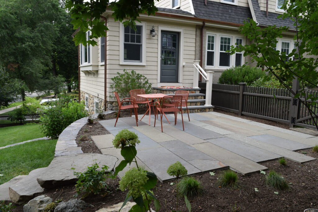 Garden Enhancement 5 A patio with chairs and a table in front of a house offers the perfect garden enhancement, creating an inviting outdoor space for relaxation and gatherings.